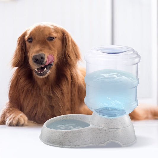 A golden retriever dog is lying on a white floor next to an automatic pet water fountain with a clear water reservoir and a gray speckled base.