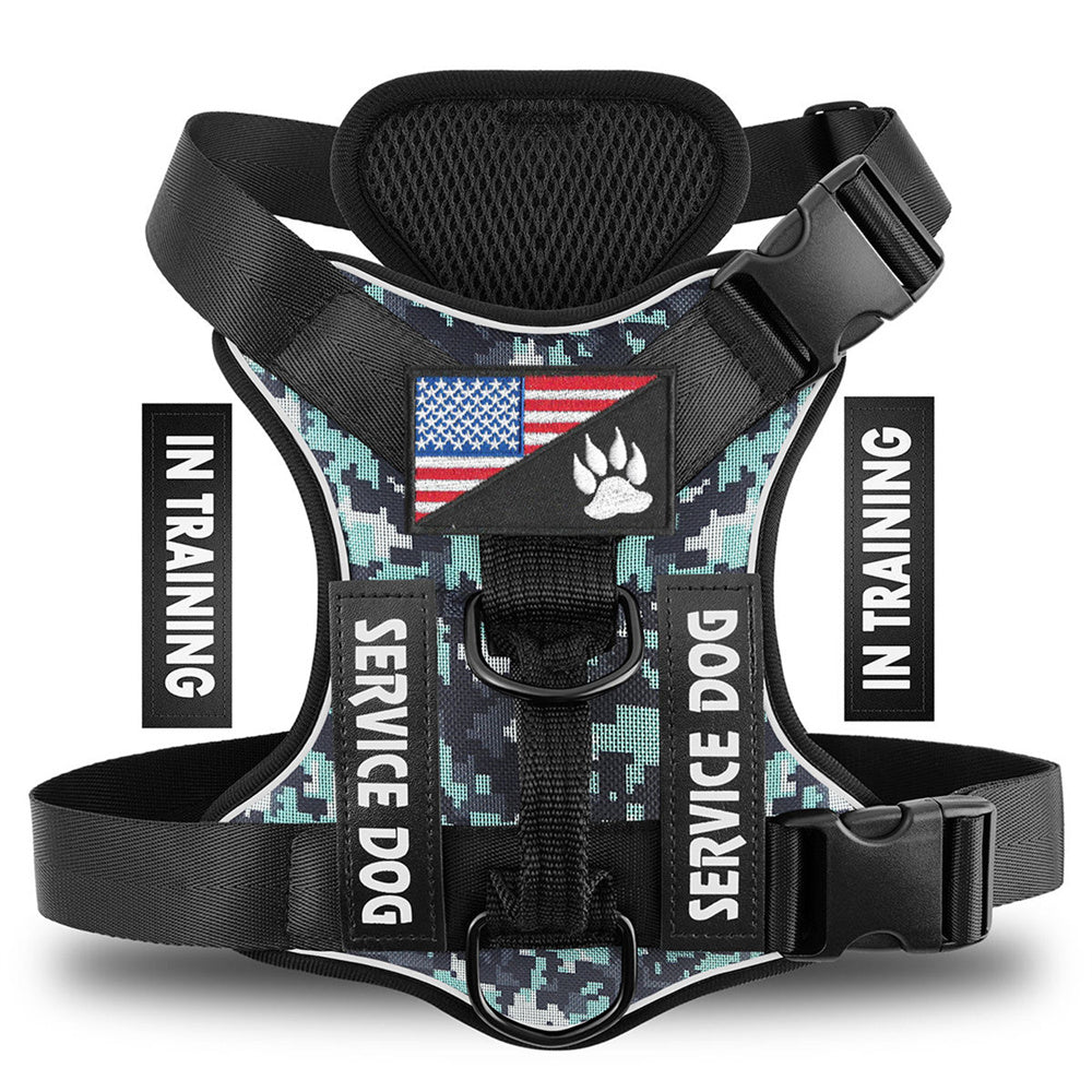 A digital camouflage dog harness with black adjustable straps and plastic buckles, featuring a central patch with an American flag and a paw print, and 'SERVICE DOG' text patches on the sides. The image includes vertical 'IN TRAINING' text overlays on both sides.